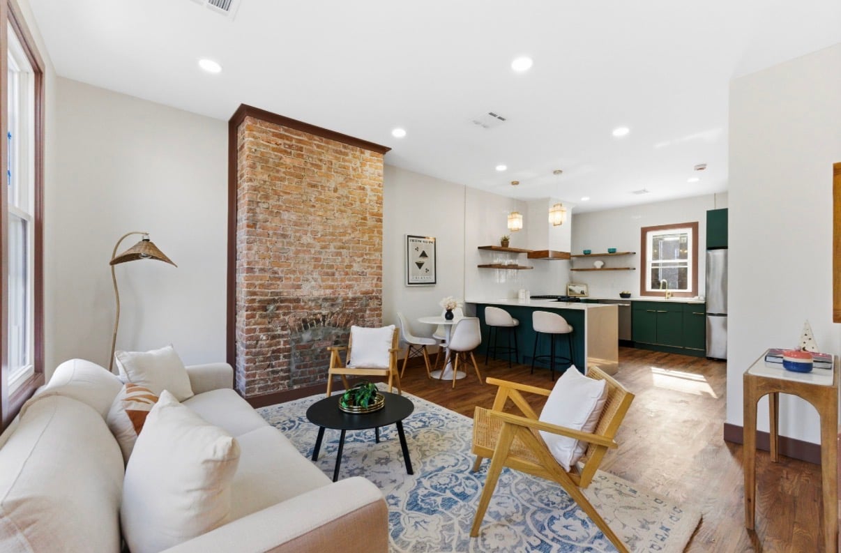Living room with restored exposed-brick chimney and green chef's kitchen beyond